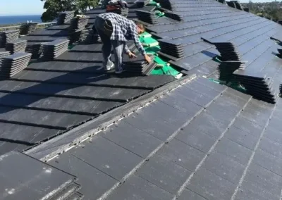 Roofers installing a new dark tiled roof in Nowra