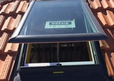 Roof window installed between terracotta roof tiles