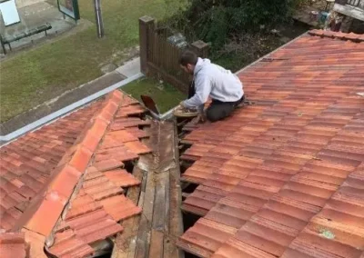 Roofer repairing a valley between terracotta roof tiles